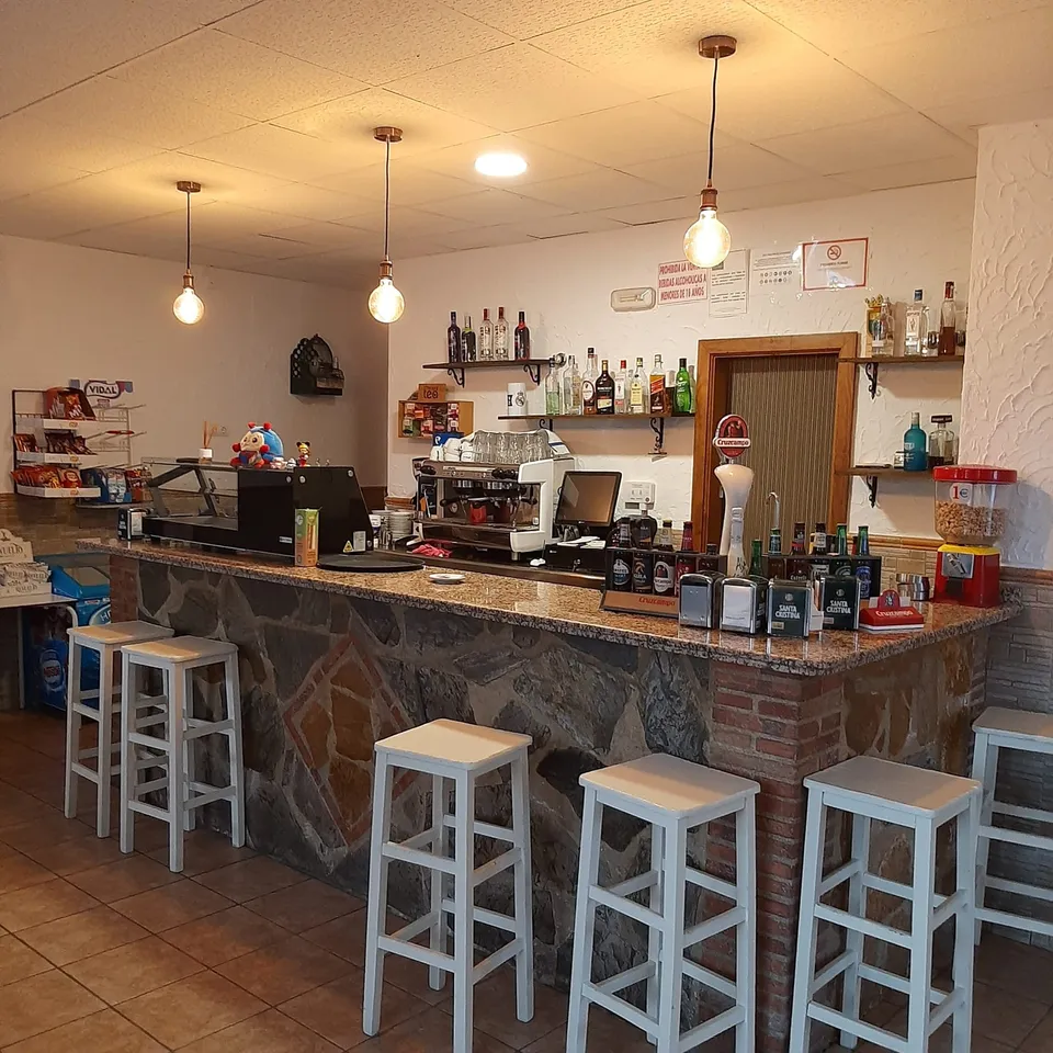 Bar con taburetes y bebidas.