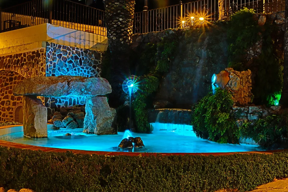 Fuente iluminada en jardín.