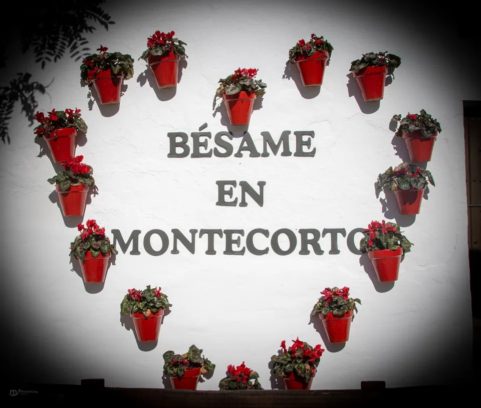 Pared blanca con macetas rojas.