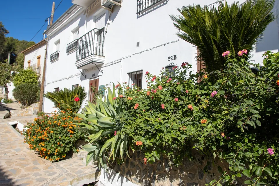 Casa blanca con jardines coloridos.